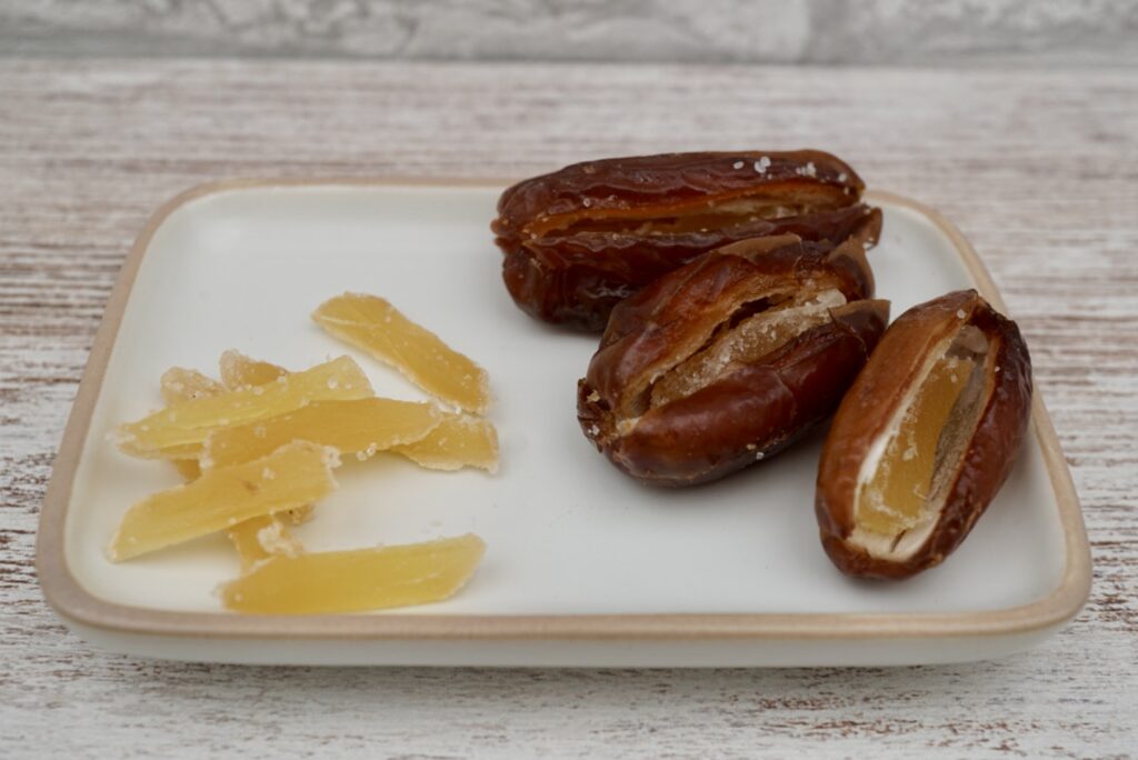 Deglet nour dates and slither of crystallised ginger on a plate