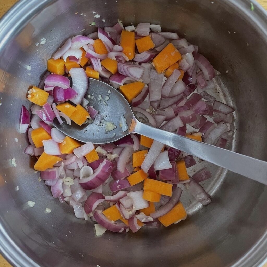Red onion, butternut squash and garlic in a pan