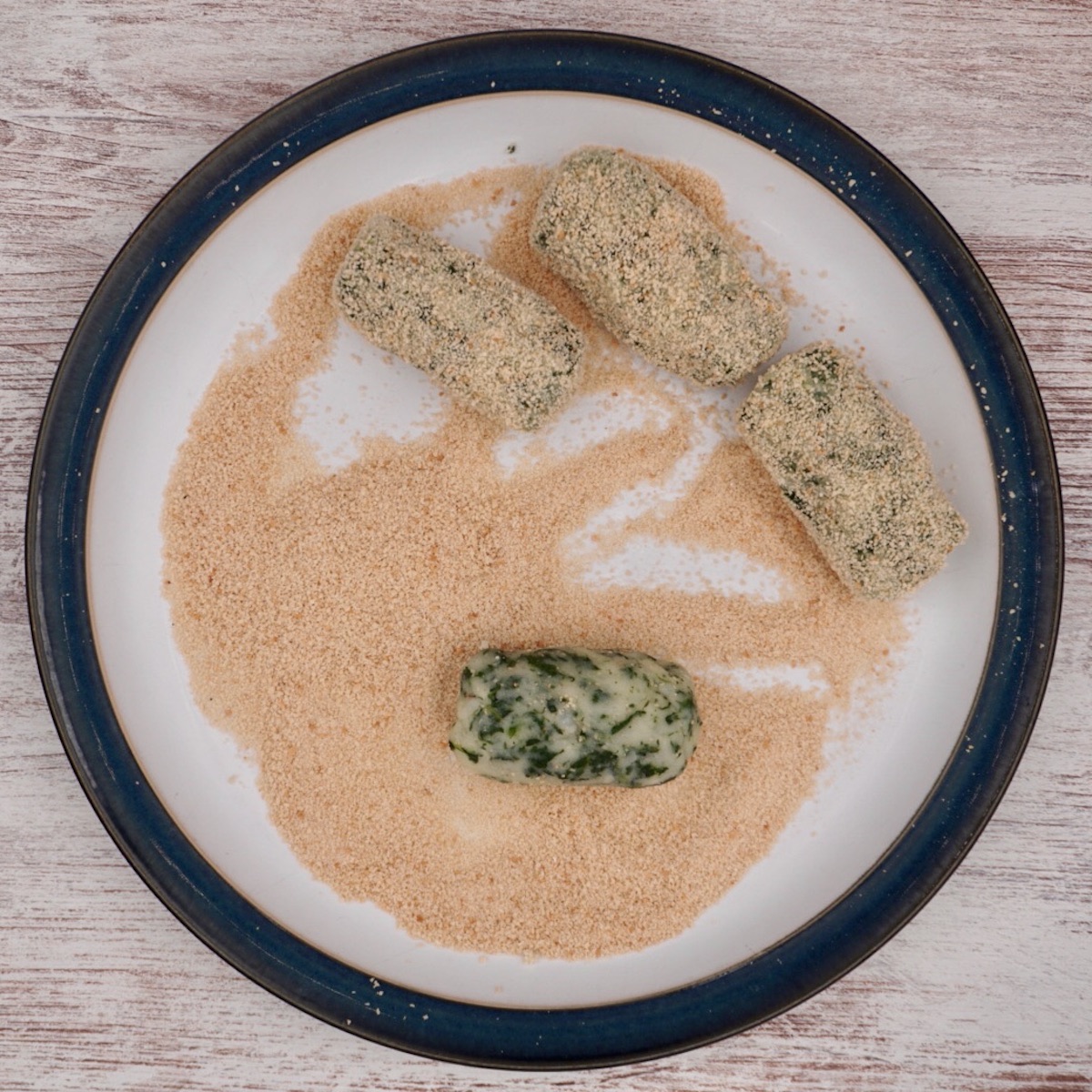 Coating spinach croquettes in breadcrumbs