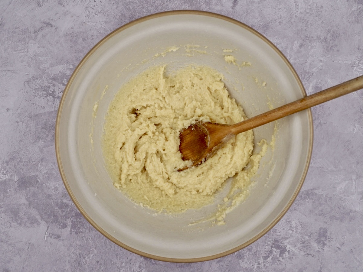 Butter and sugar in a baking bowl with a wooden spoon