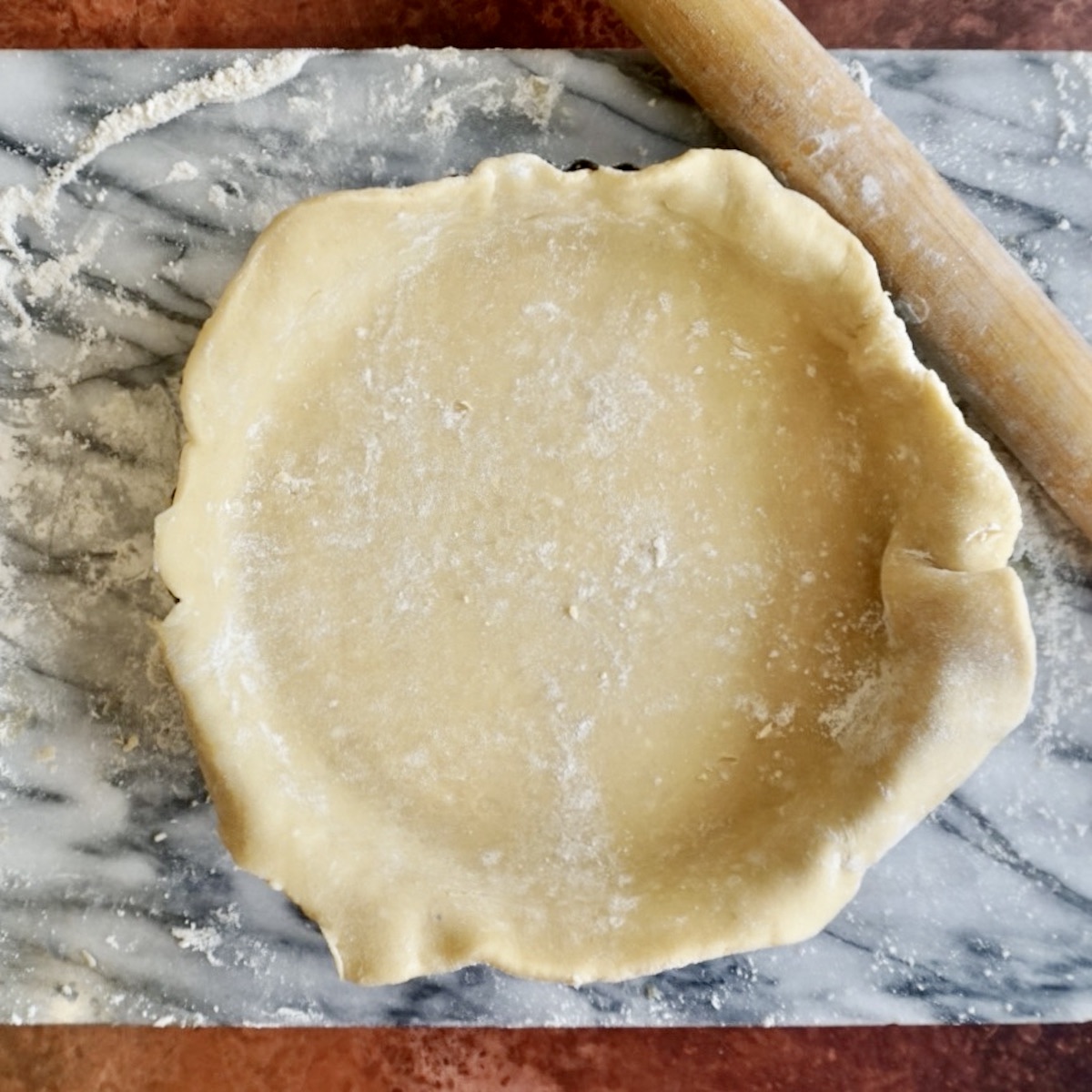 A tart dish lined with pastry with edges untrimmed. 