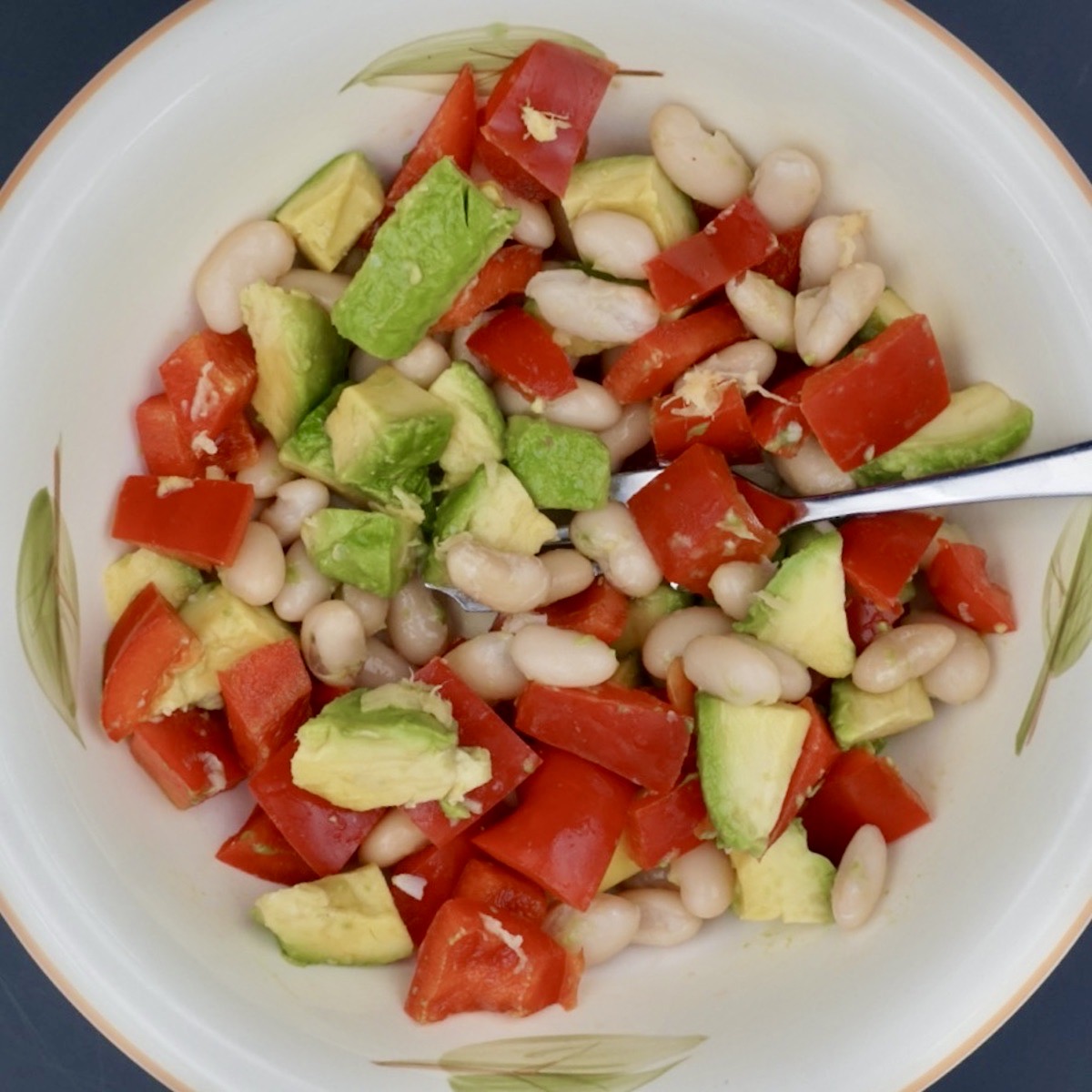 Overhead view of a bowl of avocado and red pepper salad with beans