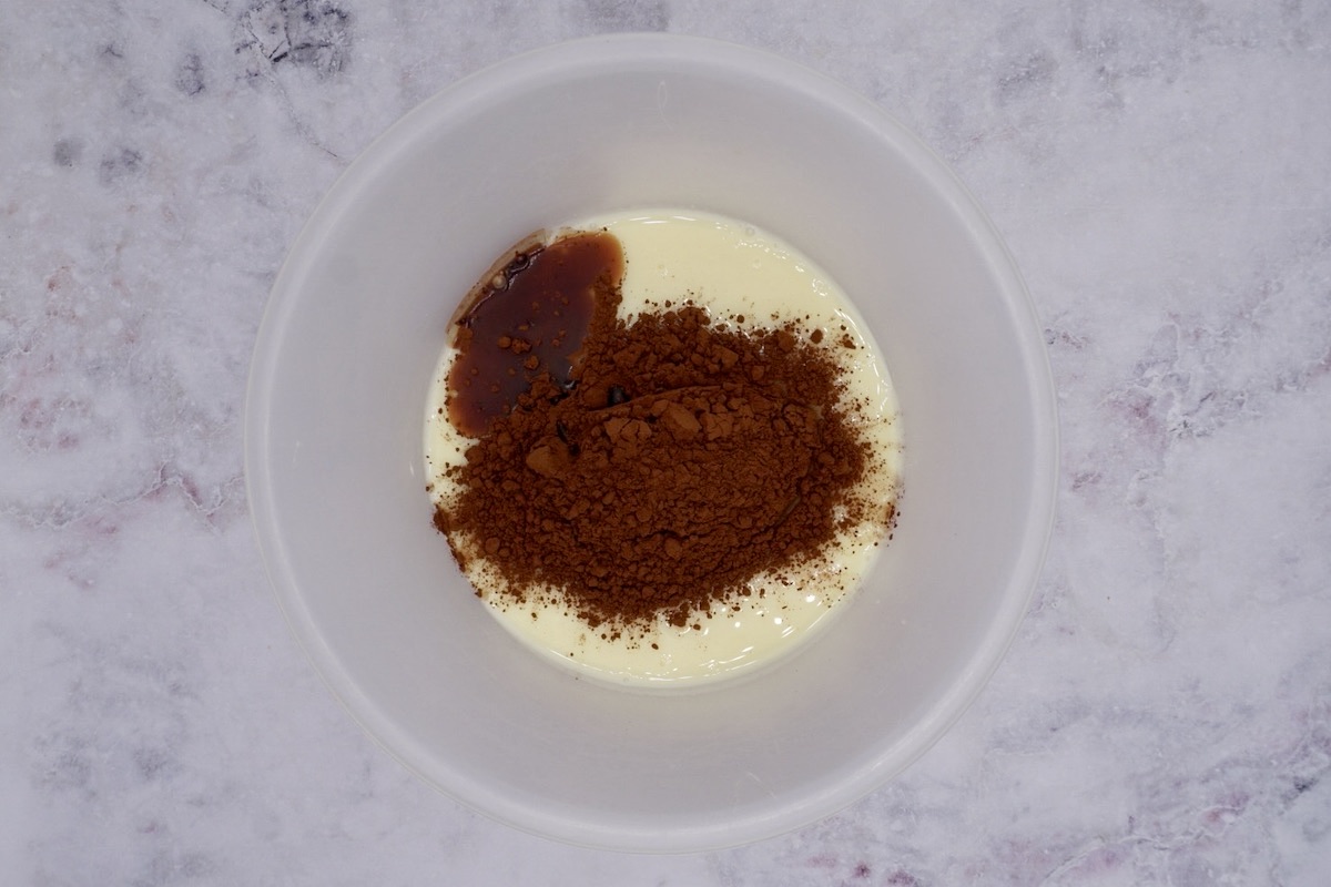 Condensed milk, cocoa powder and vanilla essence in a bowl