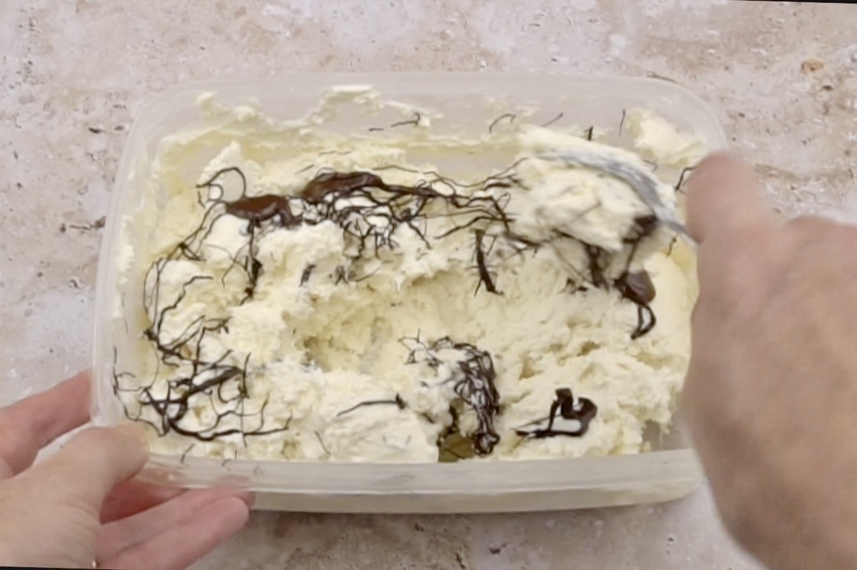 Adding chocolate strands to make stracciatella ice cream