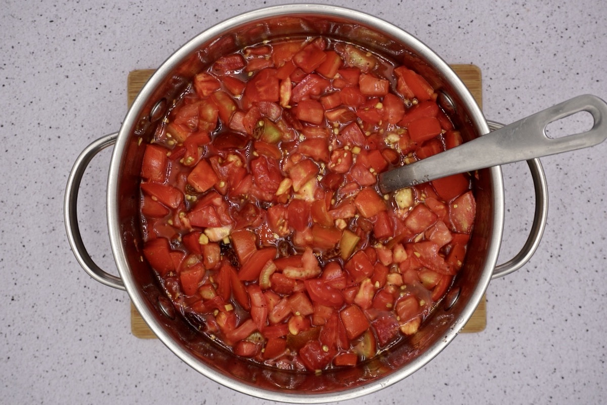 A pan containing ingredients to make red tomato chutney.