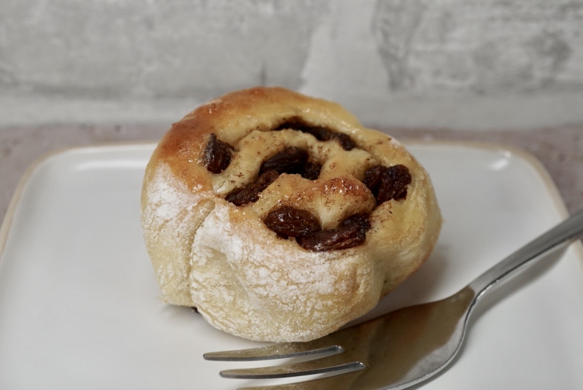 A single cinnamon roll on a plate with a fork