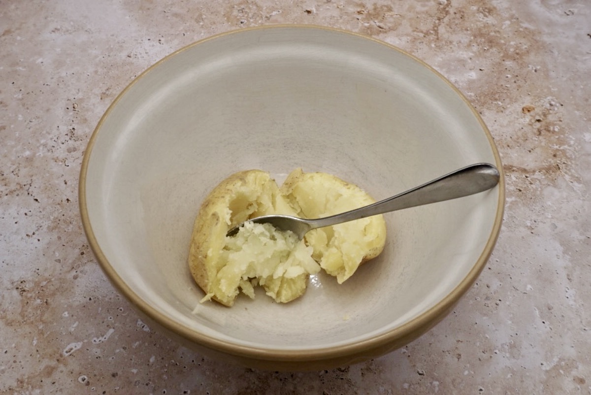 Cooked potato being scooped from a potato