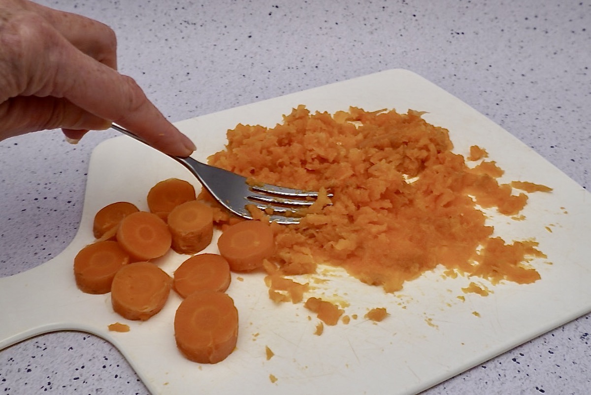 Partly mashed carrots on a board