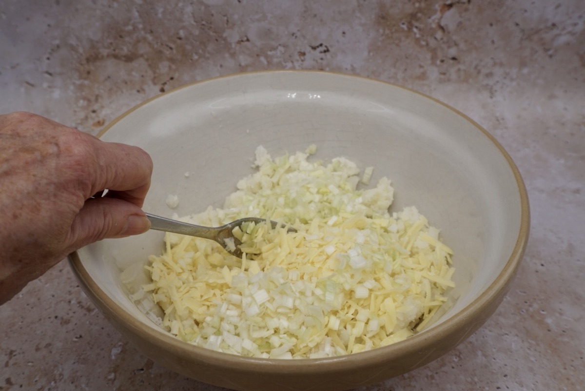 Mashed potato, grated cheese and chopped leek in a bowl