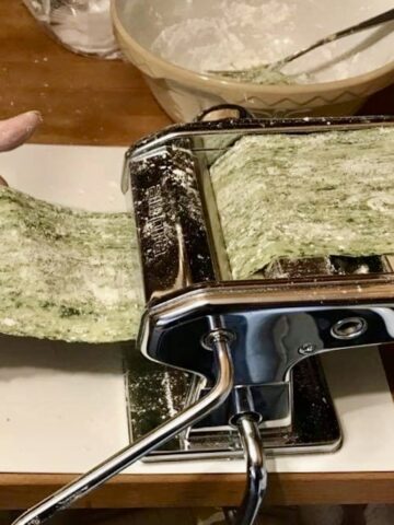 Rolling spinach pasta in a pasta machine