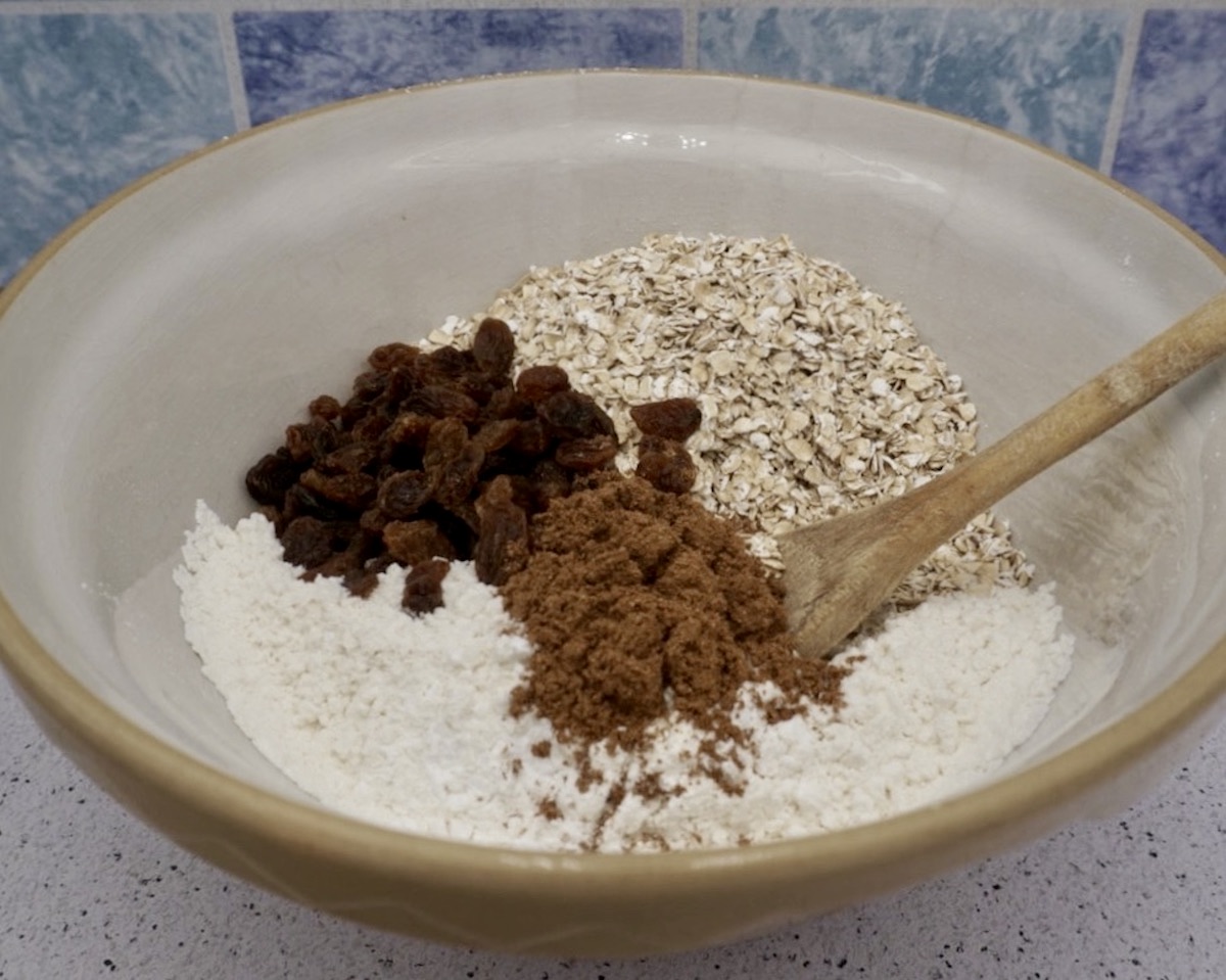 A bowl containing biscuit ingredients and a wooden spoon. 