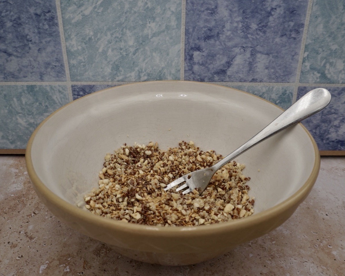 A bowl of quinoa, chopped nuts and seeds