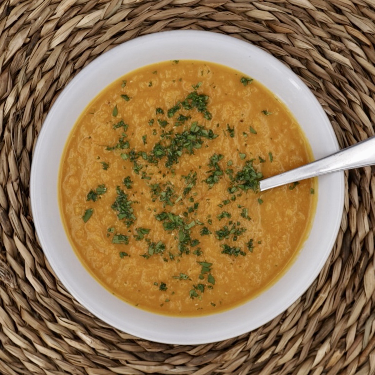 Overhead view of a bowl of spicy carrot and lentil soup.