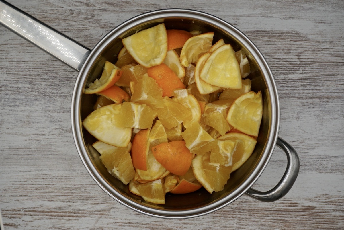 Overhead view of chopped up orange and orange peel in a pan.