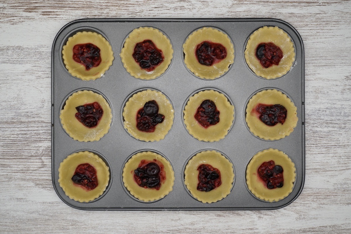 A tray of twelve pastry cases with fruit filling.