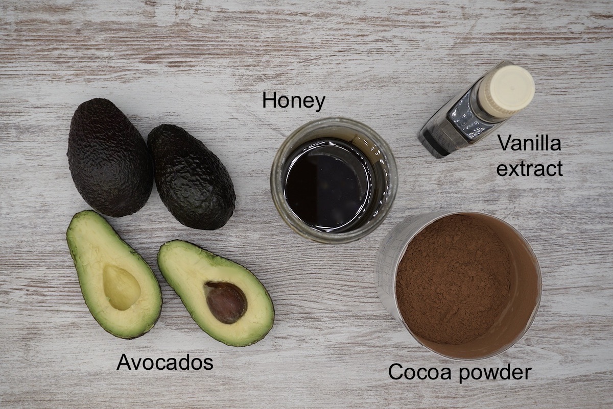 Avocados, honey, vanilla extract and cocoa powder with labels.