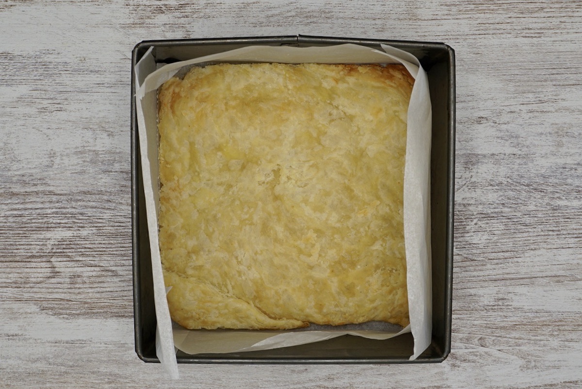 A square tin with cooked pastry inside.