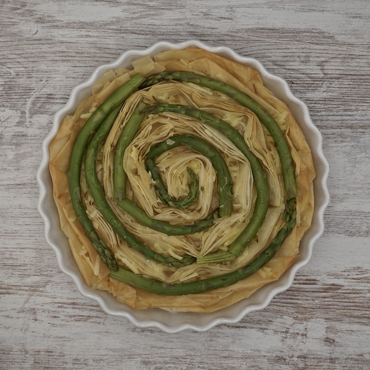 A filo tart case with asparagus formed in a spiral.