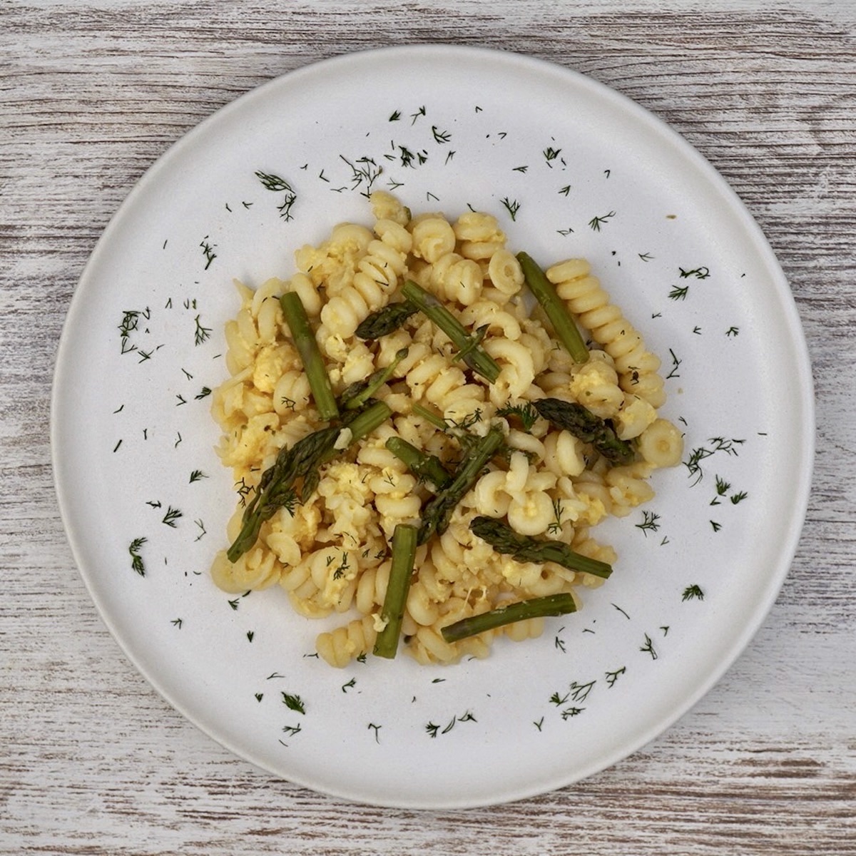 A plate of pasta with scrambled eggs and asparagus.