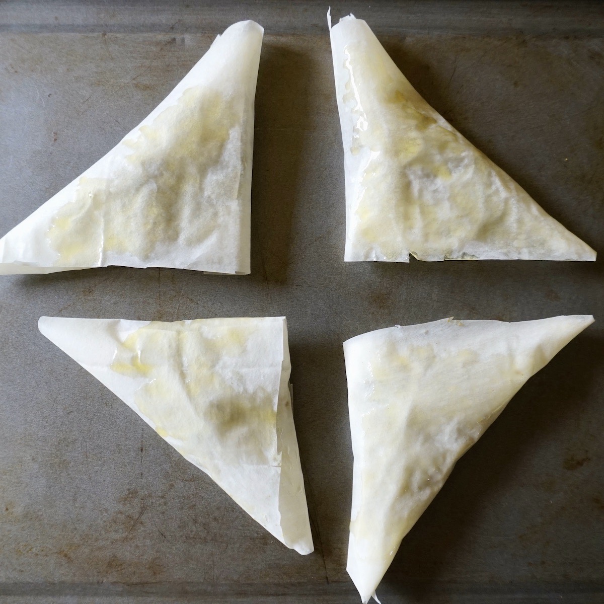 Unbaked filo pastry triangles.