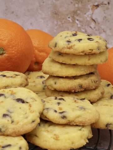 A stack of homemade biscuits with oranges behind.