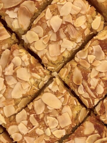 Several slices of almond cake topped with almonds.