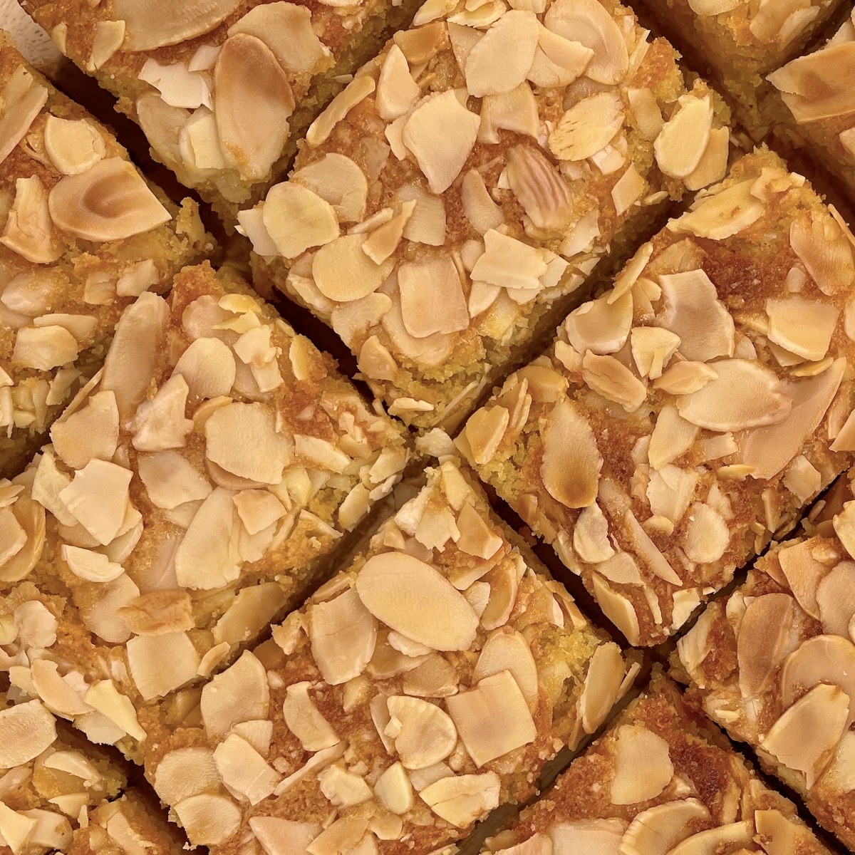 Several slices of almond cake topped with almonds.
