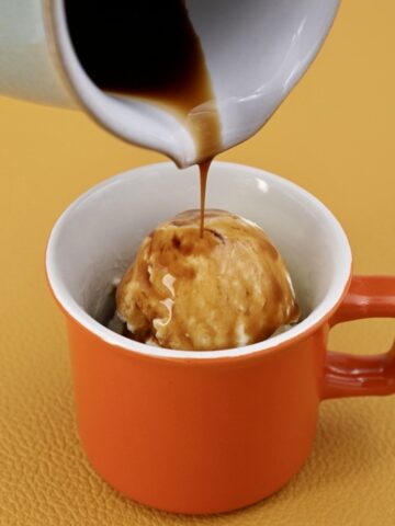 Coffee being poured from a jug onto a cup of ice cream to make affogato.