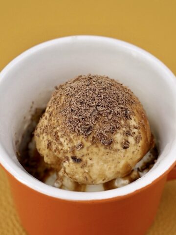 Affogato ice cream dessert in a small orange cup.