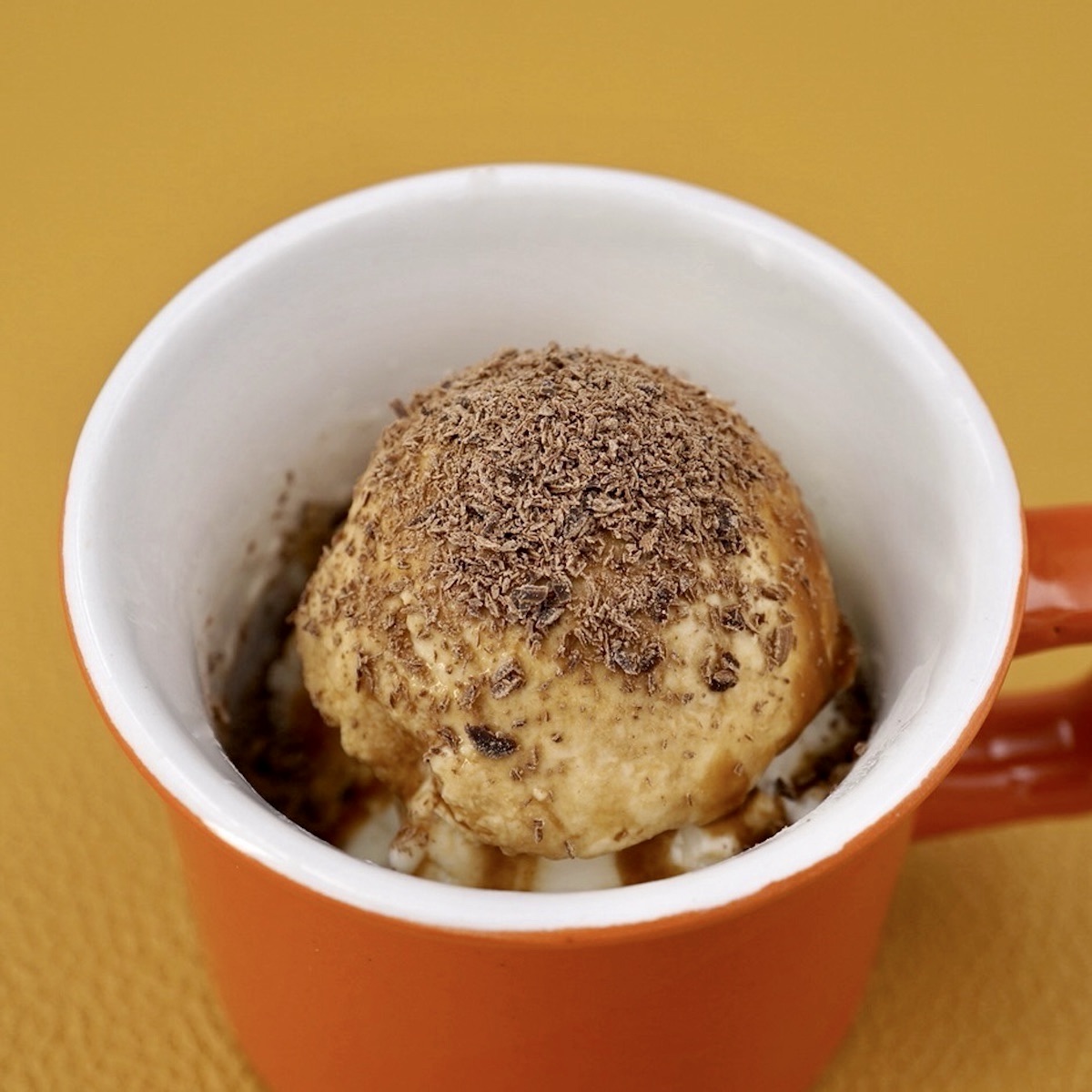 Affogato ice cream dessert in a small orange cup.