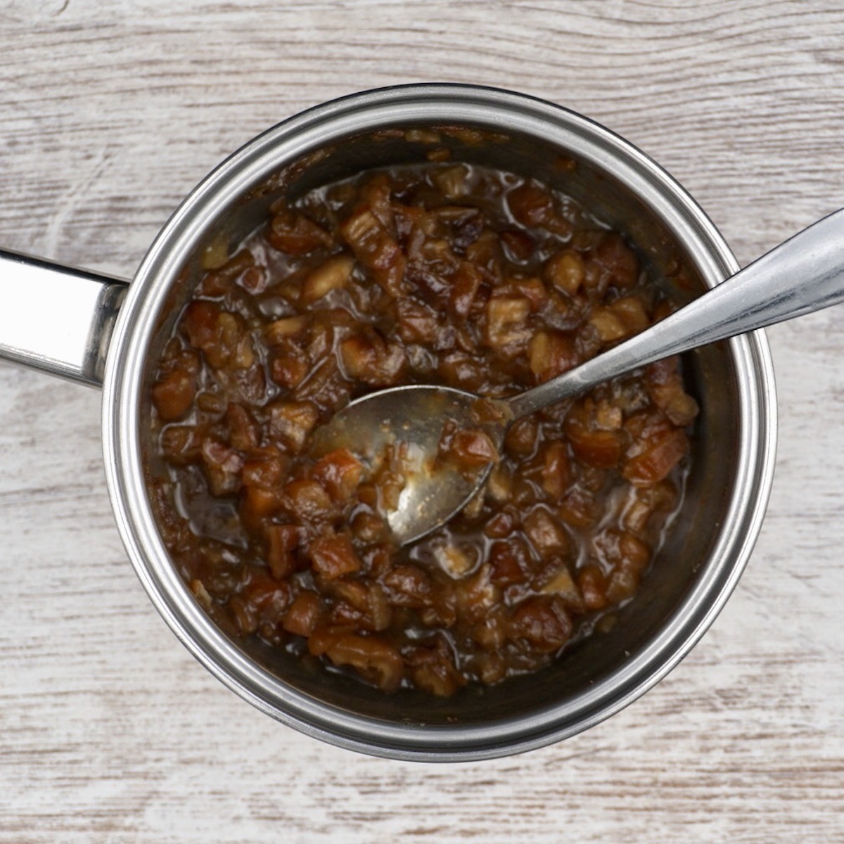Date paste in a pan with a spoon.