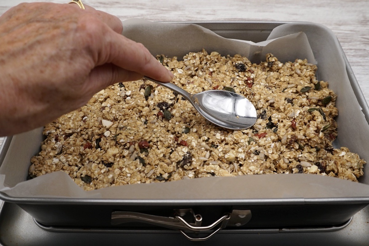 Granola mixture being packed into a tin.