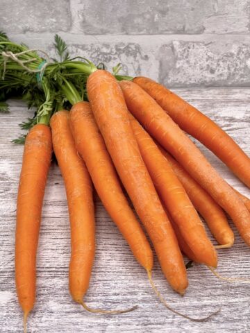 A bunch of homegrown carrots on a kitchen worktop.