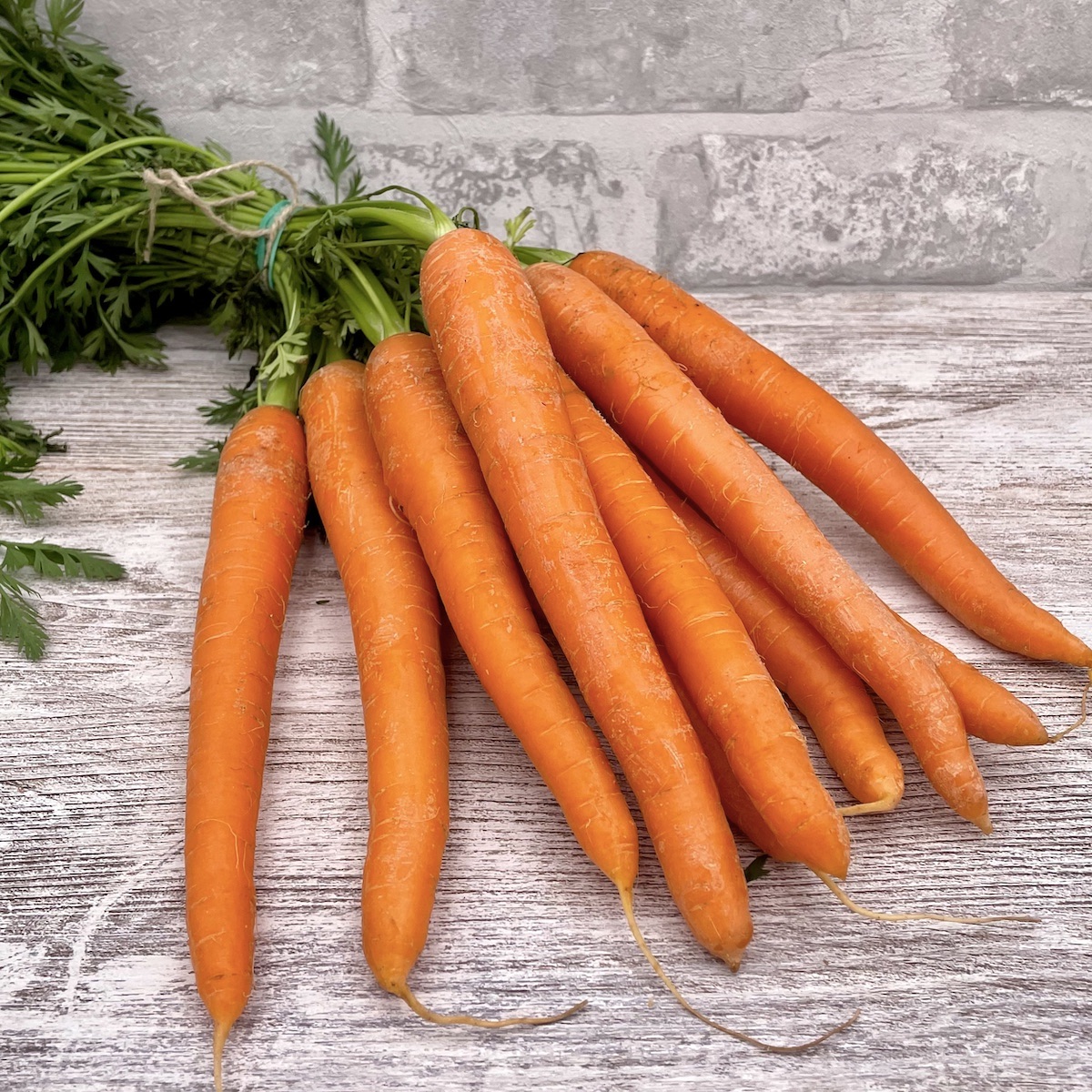 A bunch of homegrown carrots on a kitchen worktop.