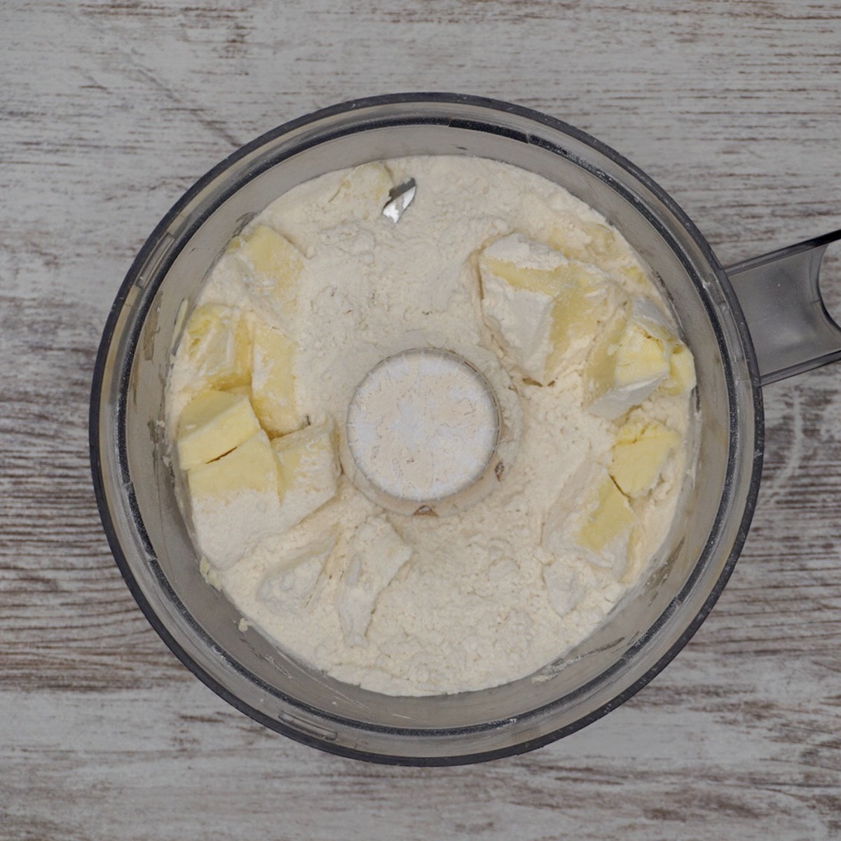 Flour and butter in a food processor bowl.