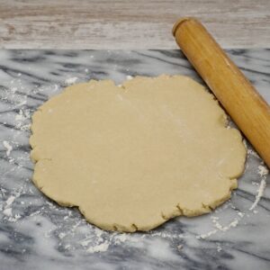 Pastry rolled out on a board next to a rolling pin.