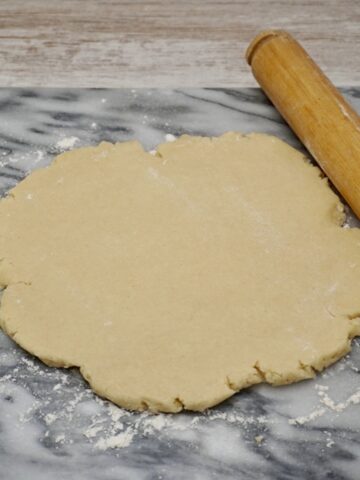 Pastry rolled out on a board next to a rolling pin.