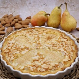 Pear and almond tart next to some pears and almonds.