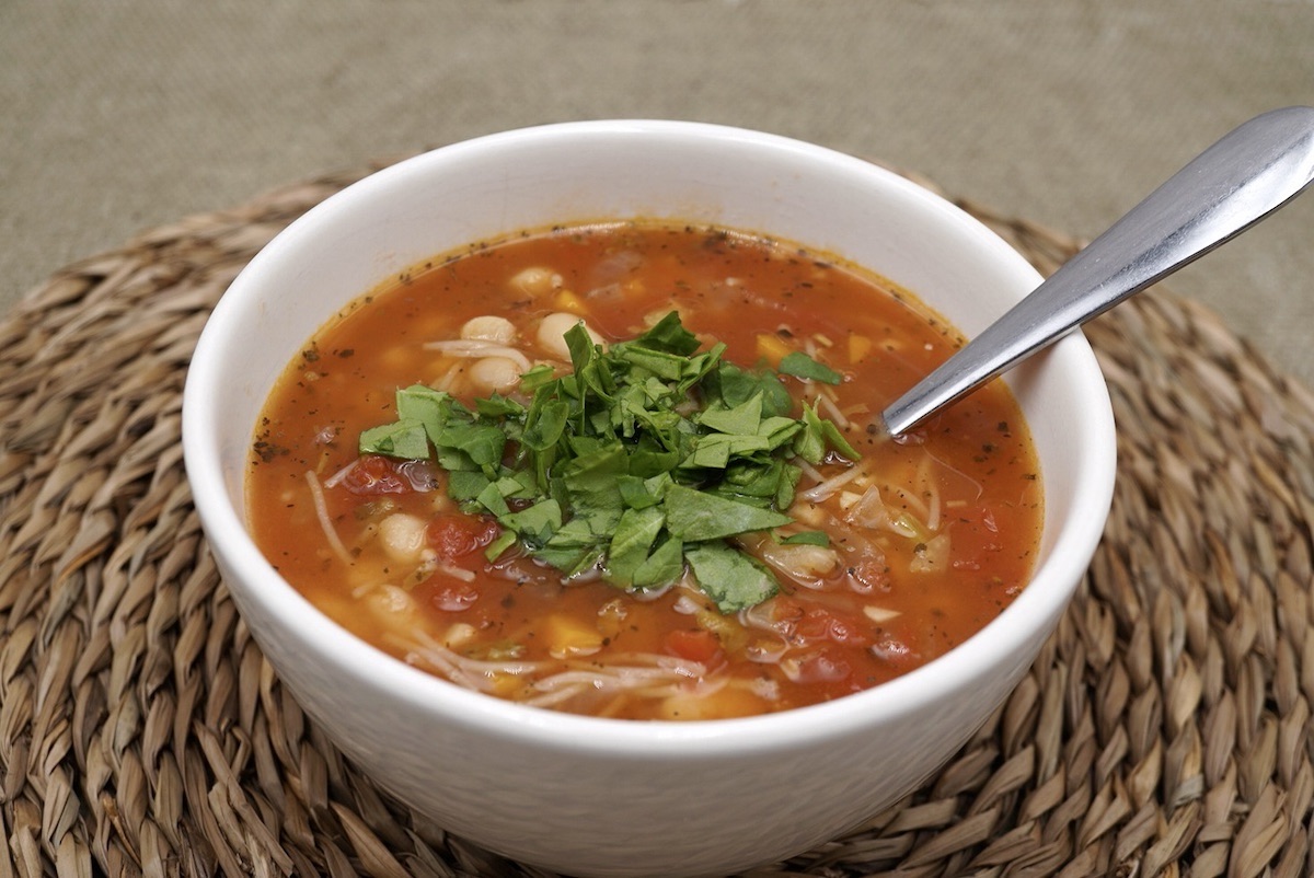 A bowl of tomato and bean soup with spinach garnish.