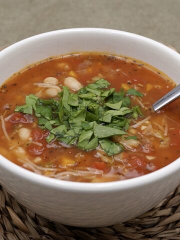 A bowl of tomato and bean soup with spinach garnish.