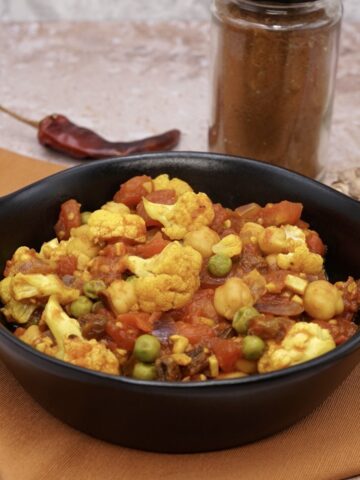 A serving bowl containing cauliflower and chick pea curry.