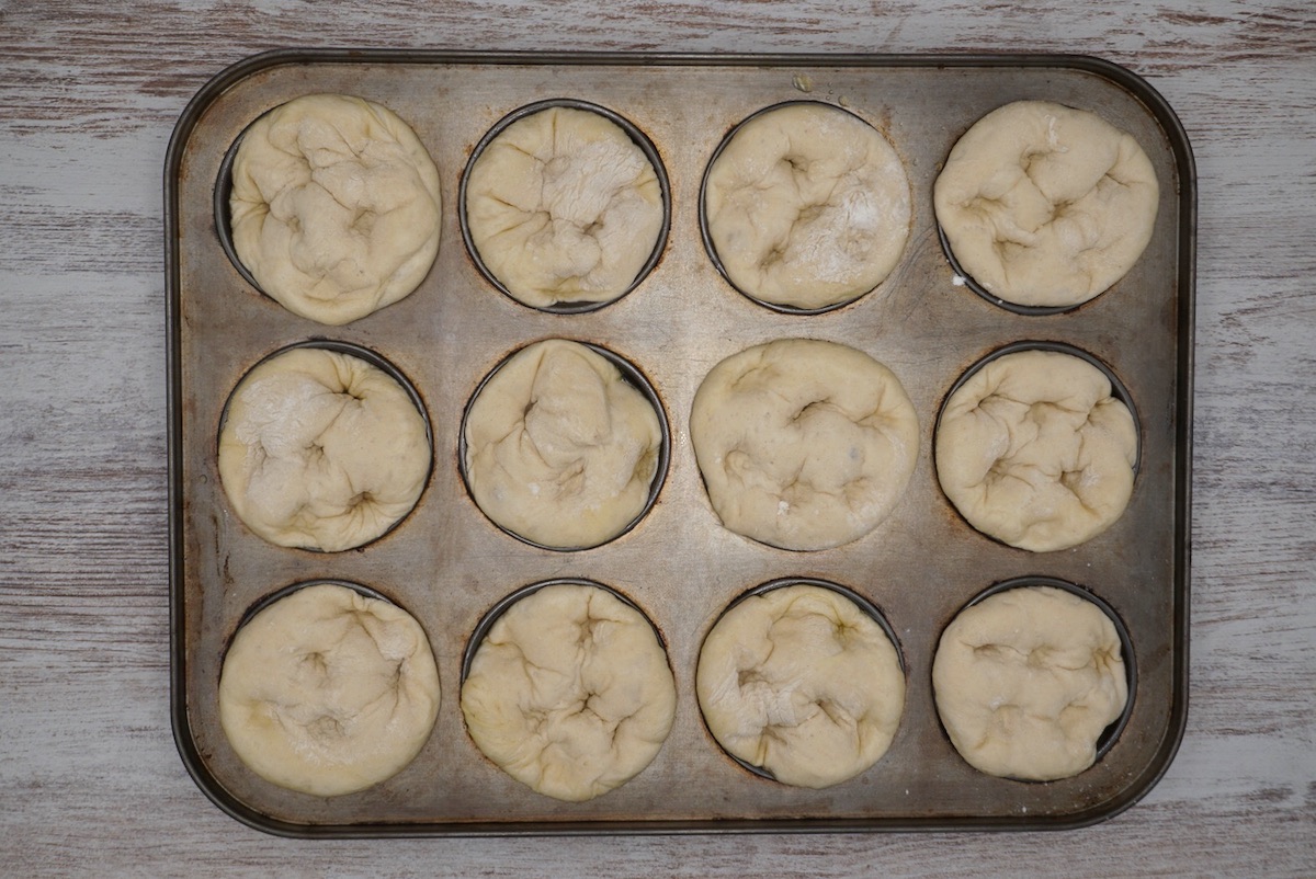 Twlelve unbaked focaccia muffins in a muffin tin.