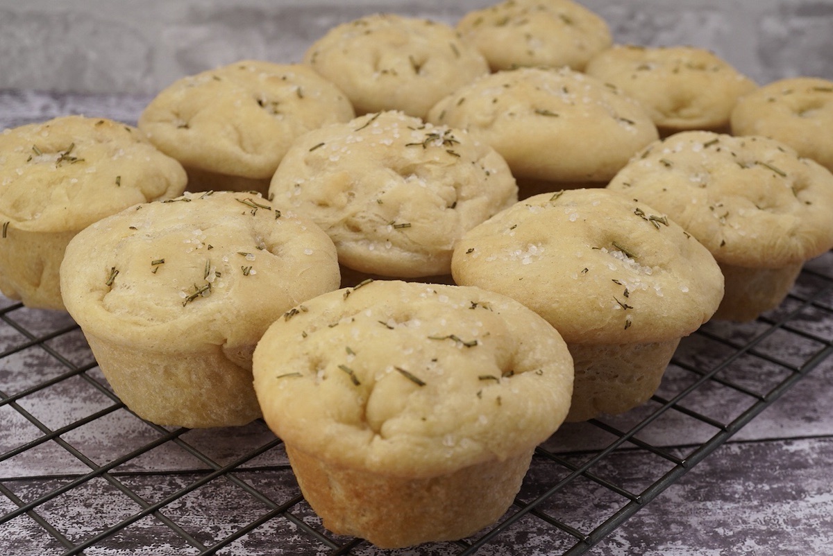 Twelve individual focaccia rolls on a wire rack.