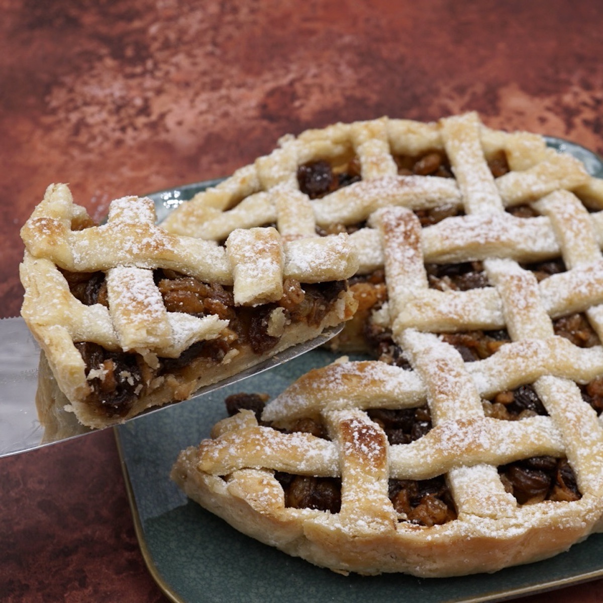 A slice of lattice tart being cut from a whole tart. 