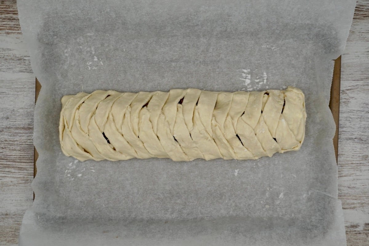 An unbaked fruit strudel on a baking sheet.