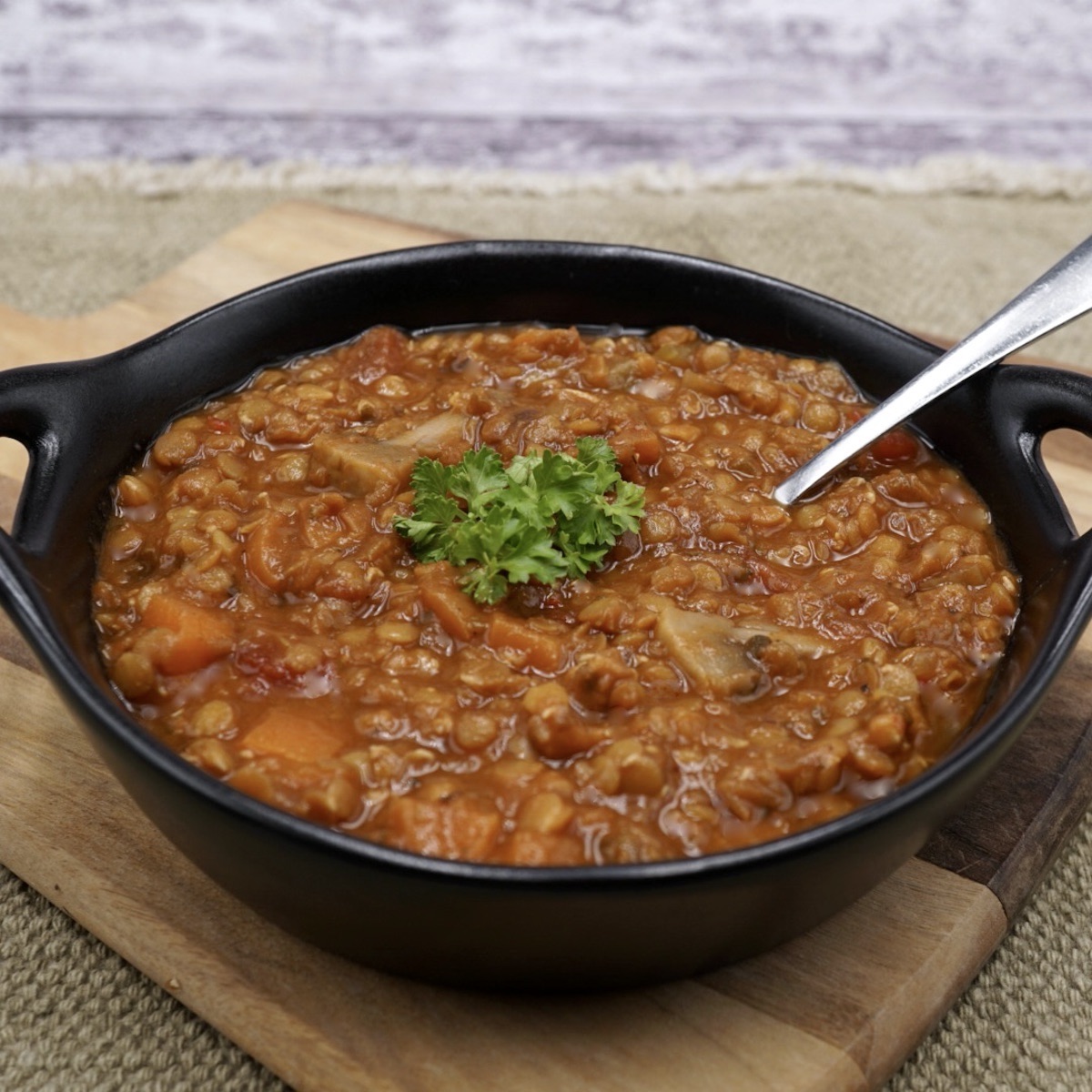 A bowl of lentil ragout stew with herb garnish. 