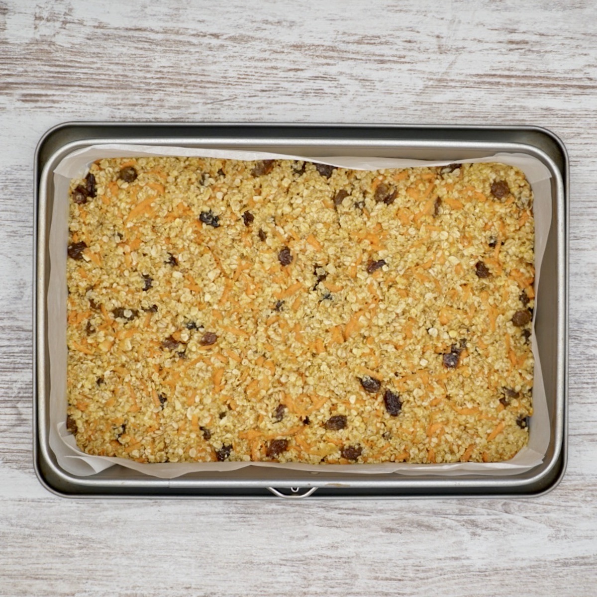 Unbaked oat and carrot flapjacks in a tin.