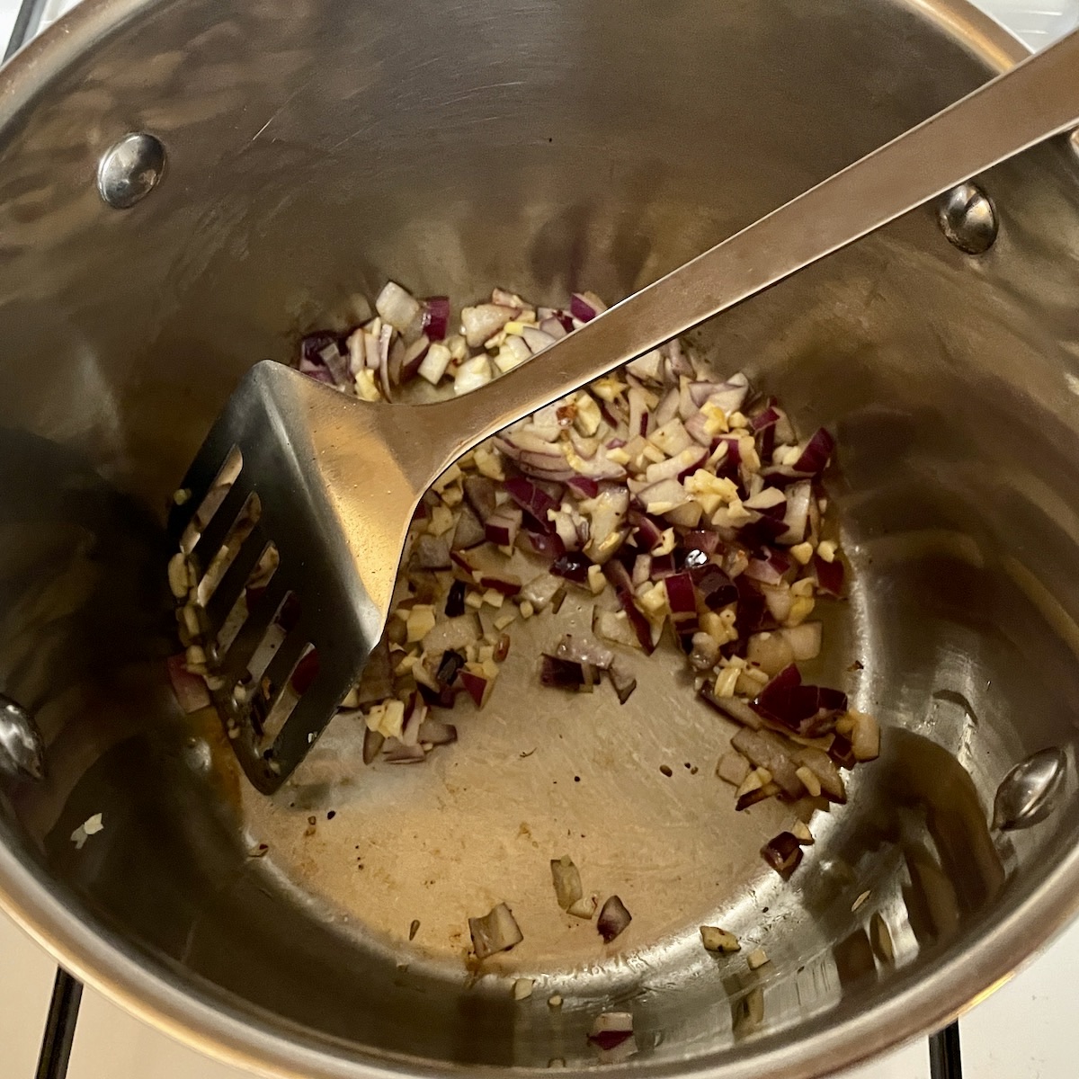 Onions and garlic being cooked in a pan.