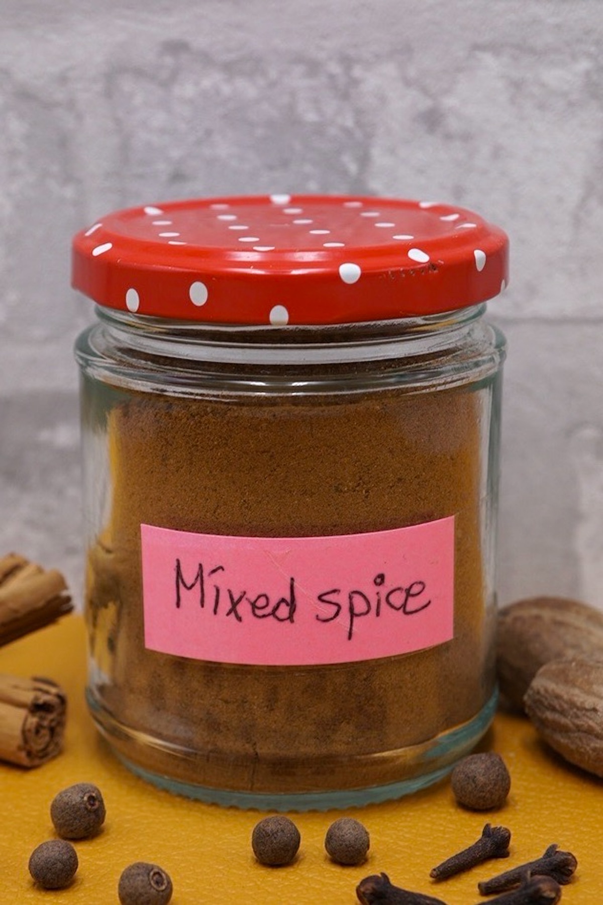 A jar of mixed spice next to some whole spices.
