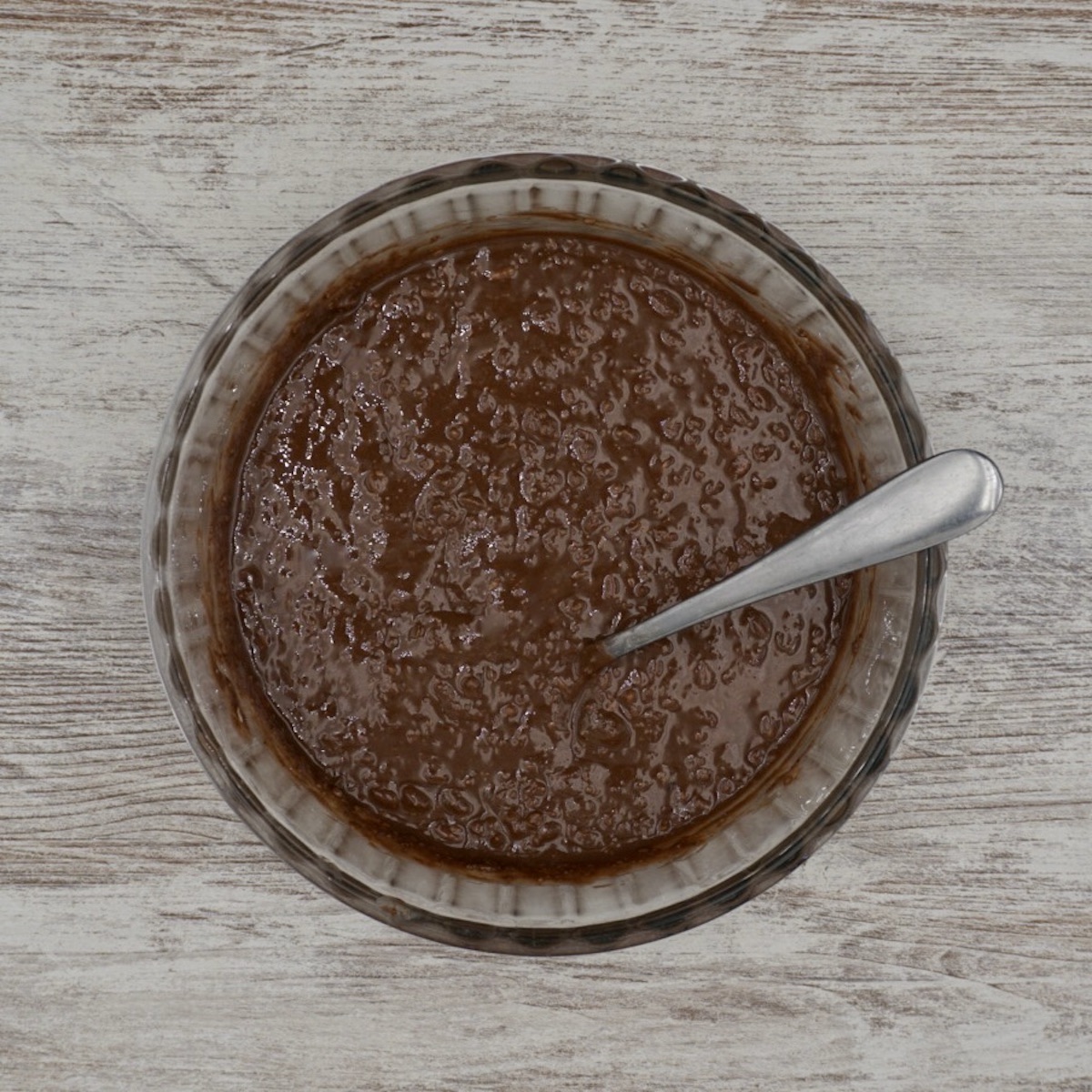 A bowl containing melted chocolate mixed with dried ingredients.